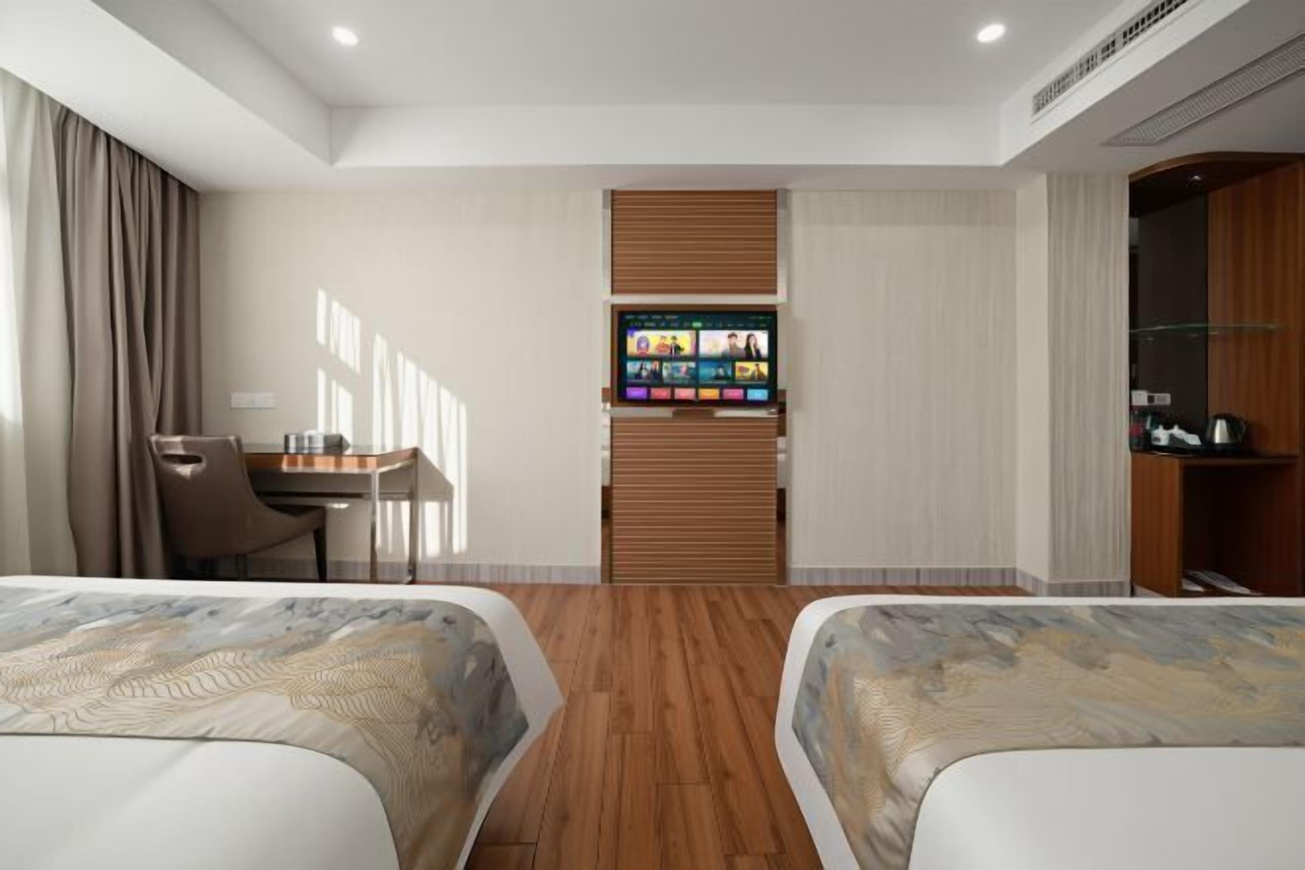 Une chambre d’hôtel avec deux lits, un bureau, une télévision et une armoire.