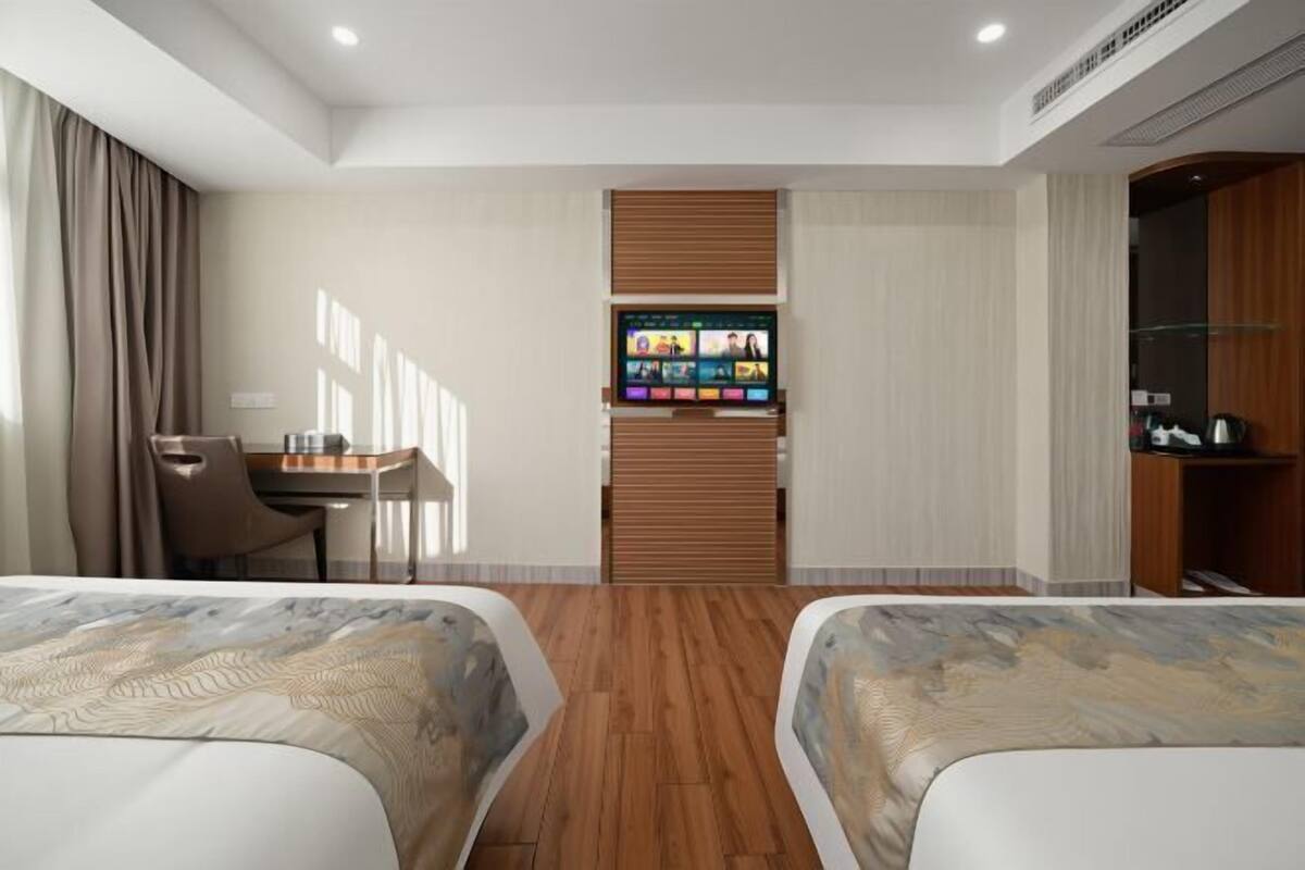 Una habitación de hotel con dos camas, un escritorio, un televisor y un armario.