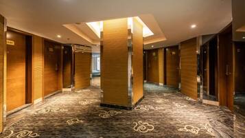 Un couloir d’hôtel avec des portes en bois, une moquette à motifs et un pilier central.