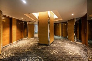 A hotel corridor with wooden doors, a patterned carpet, and a central pillar. - Park Lane Yiju Hotel (Taishan Commercial City Qiaohu Road) (Taishan)