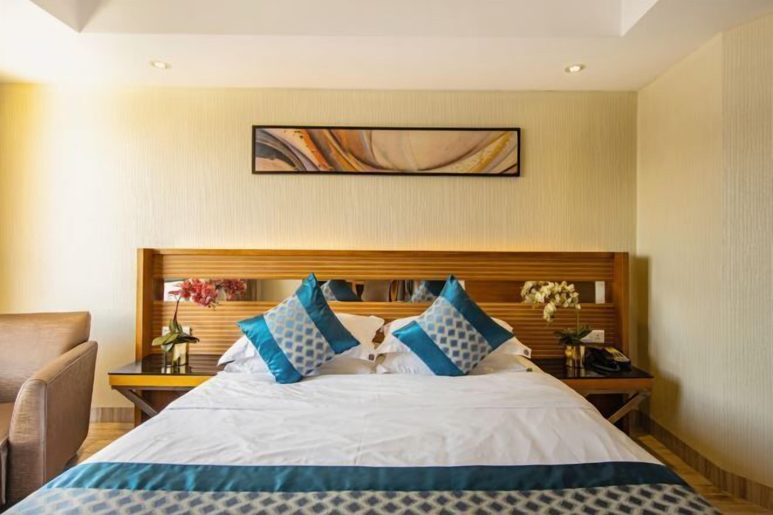 A hotel room with a bed, nightstands, a chair, and a painting on the wall.
