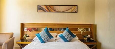 A hotel room with a bed, nightstands, a chair, and a painting on the wall.