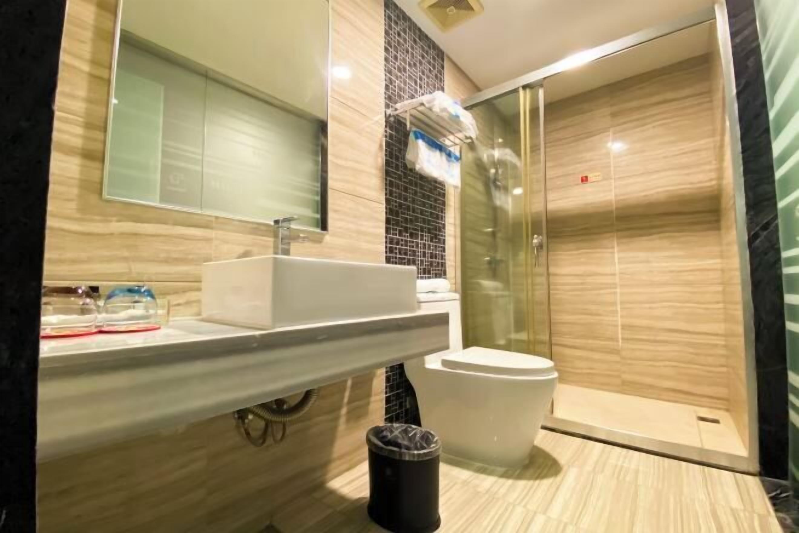 Un baño moderno con ducha acristalada, lavamanos blanco y espejo sobre él.
