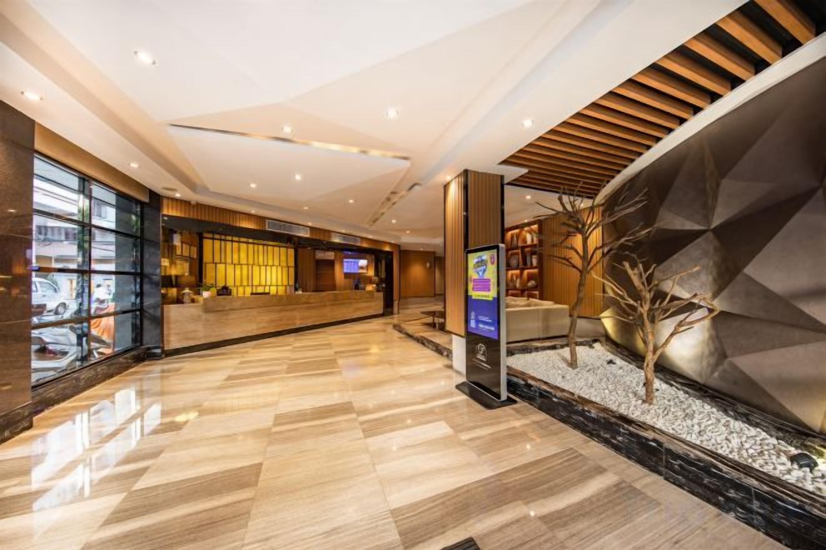 A hotel lobby with a reception desk, seating area, and a decorative wall.