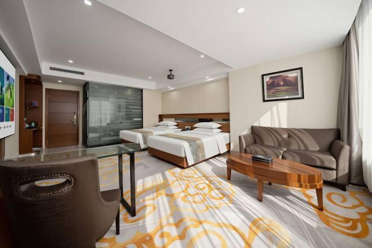 Una habitación de hotel con cama, sofá, mesita de café y televisión.