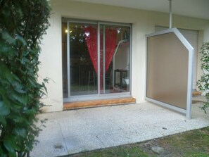 Un bâtiment doté d’une porte en verre, d’un petit porche et d’un sol en béton.
