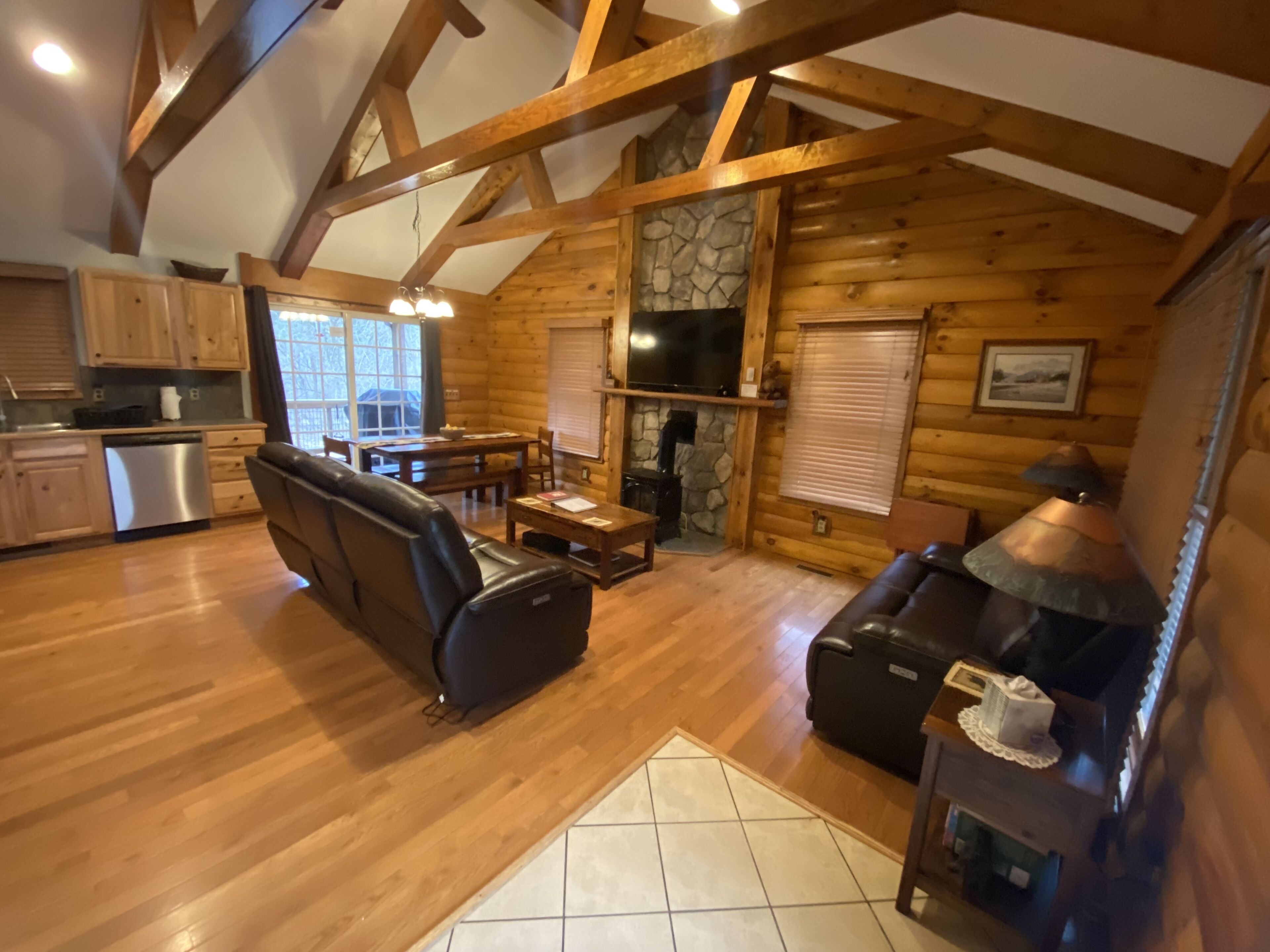 A log cabin interior with a dining area, seating, a fireplace, and a kitchen.