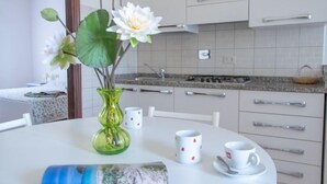 A modern kitchen with white cabinets, a granite countertop, and a dining table with a vase of flowers.