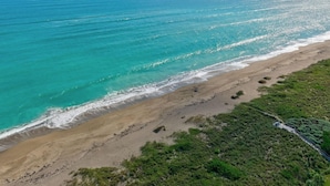 Un paysage côtier avec une plage de sable et une vue dégagée sur l’océan.