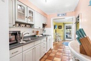 Compact kitchen with microwave, sink, and dining area.