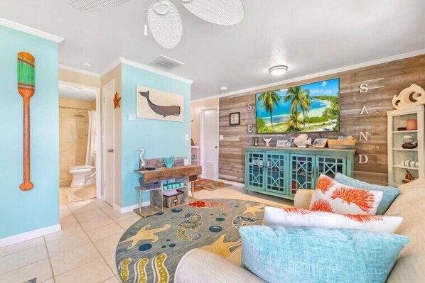 Relax in this inviting living room with a comfortable sofa, colorful artwork, and ample storage.