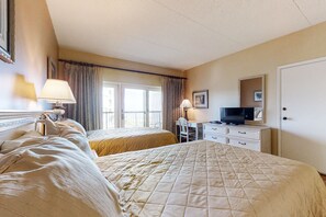 Classic hotel room with two beds, a desk, and a television.