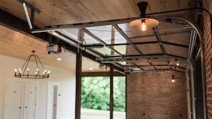 Een ruim interieur met openliggende bakstenen muren, een hoge plafond met metalen balken en een hanglamp.