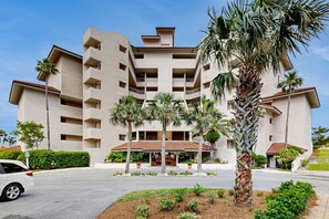 Stylish hotel with a central entrance and covered seating area, surrounded by palm trees and well-maintained landscaping.