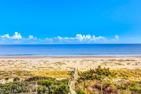 Guests can enjoy a serene ocean view from this property, with access to the beach via a pathway surrounded by lush greenery.