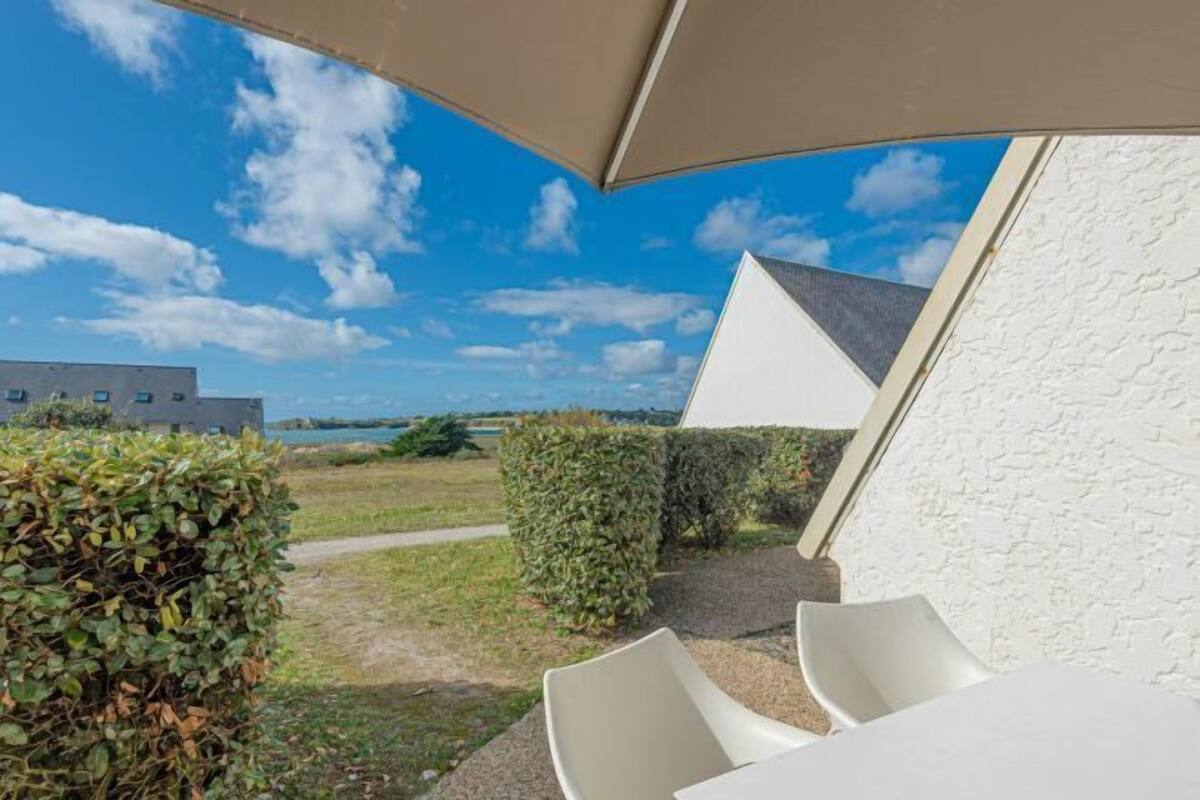 An outdoor seating area with a view of a body of water and a building in the background.