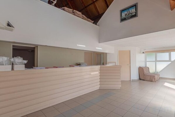 A reception area with a counter, a door, and a window. - Résidence Vacancéole – Sud Océan (Guidel)