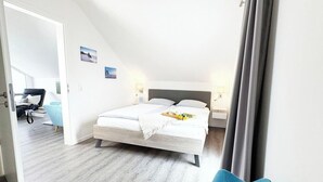 Une chambre à coucher avec un lit, des tables de chevet, une lampe et une vue sur une autre pièce.