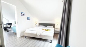 Une chambre à coucher avec un lit, des tables de chevet, une lampe et une vue sur une autre pièce.