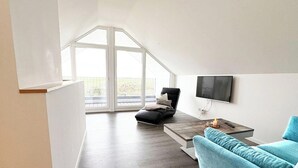 Un salon moderne doté d’une grande fenêtre, d’un téléviseur à écran plat, d’un canapé et d’une table basse.