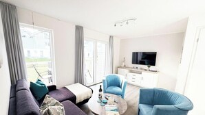 Un salon moderne avec un canapé, des fauteuils, une table basse et un téléviseur.