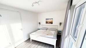 Een slaapkamer met een bed, nachtkastjes, een wandlamp en een raam.