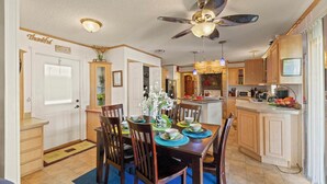 A spacious kitchen with wooden cabinets, a dining table set with chairs, and a ceiling fan.