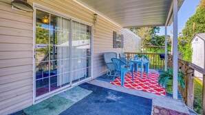 A covered porch with a red and white patterned rug, a table, and chairs.
