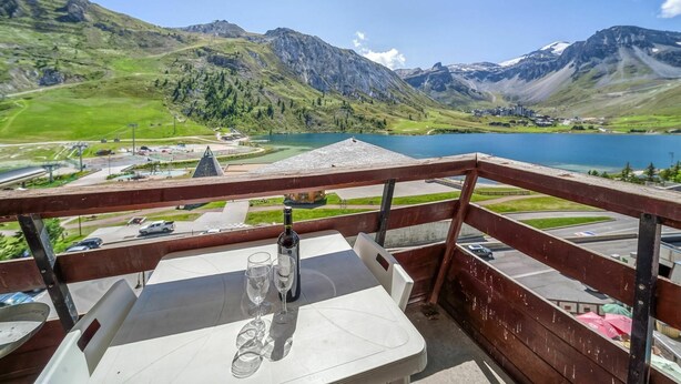 A balcony with a table, two wine glasses, and a bottle, overlooking a lake and mountains. - Cosy apartment for 4 people with WIFI, TV and balcony (Les Boisses)