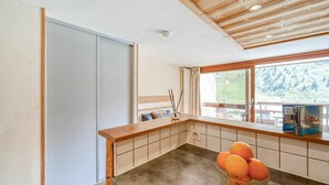 A modern kitchen with a wooden countertop, a bowl of oranges, and a view of a mountainous landscape through the window. - Cosy apartment for 4 people with WIFI, TV and balcony (Les Boisses)
