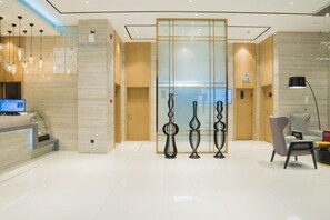 A hotel reception area with a reception desk, a glass partition, and a seating area with chairs. - City Comfort Inn Hotel (Tian'e Bus Terminal) (Tian'e)