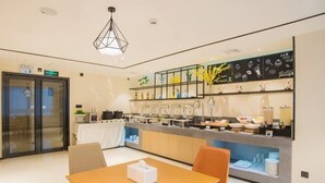 Une chambre d’hôtel moderne dotée d’un coin repas, d’un comptoir de cuisine avec divers ustensiles et d’une porte vitrée donnant sur un balcon.
