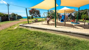 Un parque infantil con columpios, un tobogán y una zona de juegos de arena.