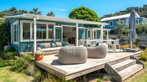 Una casa costera con terraza, mobiliario exterior y vista al océano.