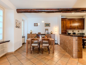 A kitchen with wooden cabinets, a tiled floor, a dining table with chairs, and a built-in island with a sink. - Lungolago by Interhome (Lecco)
