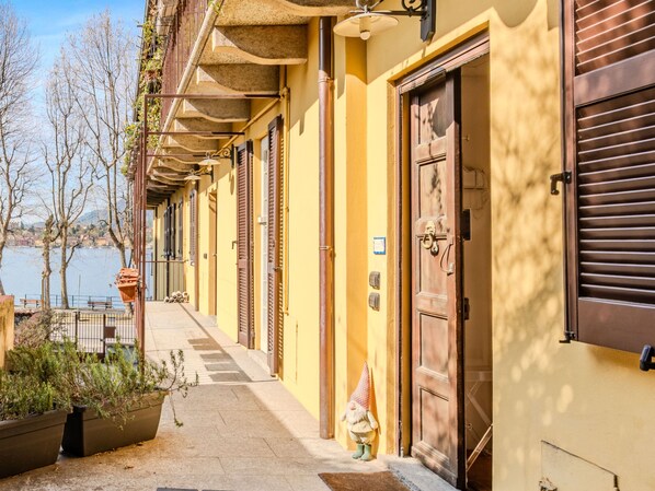 Traditional Mediterranean-style buildings line a serene pathway, featuring doors with keyholes and decorative gnomes.