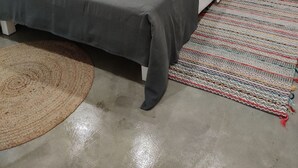 Une chambre à coucher comprenant un lit, une table de chevet, une lampe fixée au mur et une décoration murale tissée.