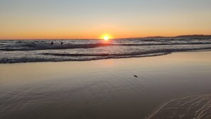 Une plage au coucher du soleil, avec des vagues et un ciel dégagé.