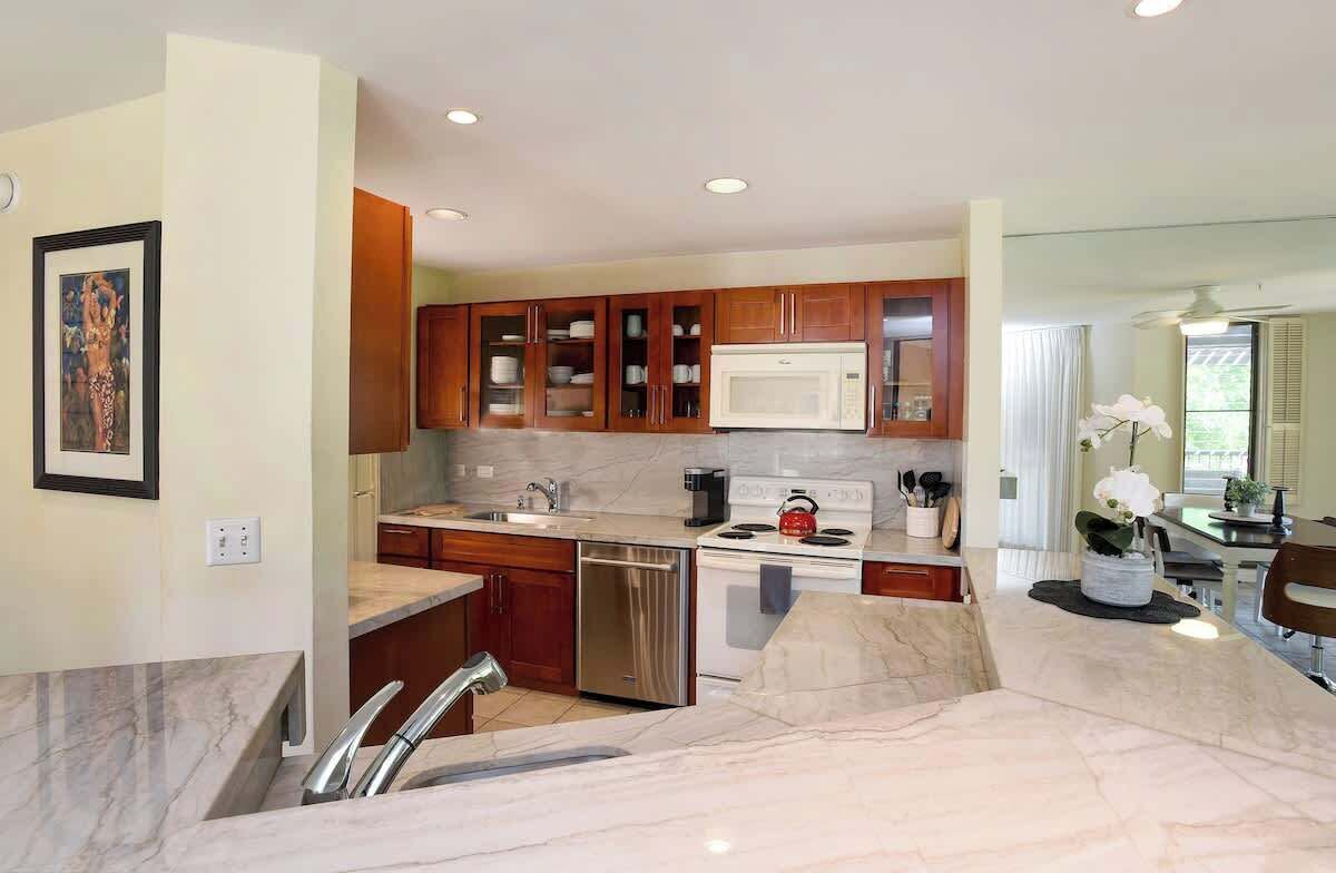 A modern kitchen with wooden cabinets, a microwave, a kettle, and a dishwasher.