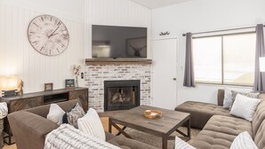 A living room with a fireplace, sofas, a coffee table, and a TV mounted above the fireplace. - 3 BR, 3 Bath sleeps 10.  Next to Giant Steps Lodge.  Ski in/out (Brian Head)
