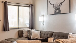 A bedroom with a large bed, a window with curtains, a wall-mounted light, and a framed picture of a yak. - 3 BR, 3 Bath sleeps 10.  Next to Giant Steps Lodge.  Ski in/out (Brian Head)