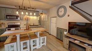 Une cuisine moderne avec des meubles en bois, un micro-ondes encastré et un coin repas comprenant une table et des bancs en bois.