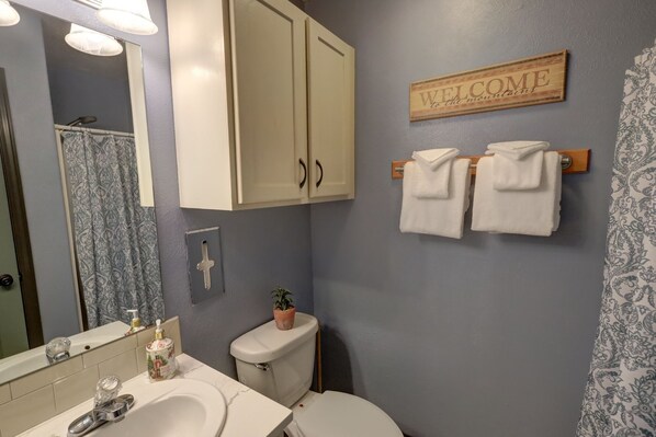 A bathroom with a sink, toilet, and a 'Welcome to the mountains' sign. - In Town Riverfront! (Red River)