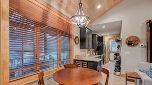 A modern kitchen with wooden blinds, a round dining table, and a chandelier. - Banner Bear - 1 mile from downtown Banner Elk, Skiing, restaurants (Banner Elk)
