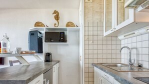 Una cocina compacta con microondas, cafetera y lavamanos.