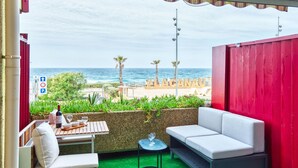 Un balcón con vista al mar, una mesa con una botella de vino y un sofá.