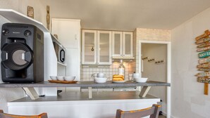 Una cocina con armarios blancos, una cafetera y un letrero de madera en la pared.