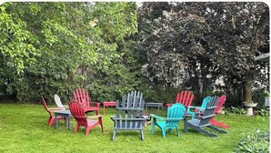 A grassy outdoor area with several Adirondack chairs in various colors arranged around a table. - Great Living Too (Berrien Springs)