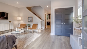 Una sala moderna con una escalera, un comedor y una cocina al fondo.