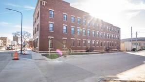 A multi-story brick building with a flat facade, large windows, and a visible entrance.